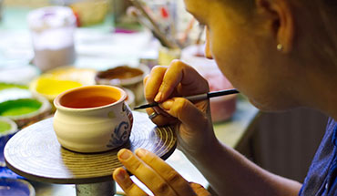 Woman up close painting a pottery bowl